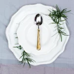 Handcrafted stainless steel teaspoon with brass handle on white ceramic plate, made in Pilimathalawa Kandy Sri Lanka