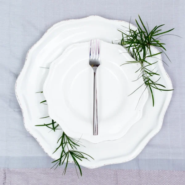 Handcrafted stainless steel dinner fork with cylindrical handle on white ceramic plate, made in Pilimathalawa Kandy Sri Lanka