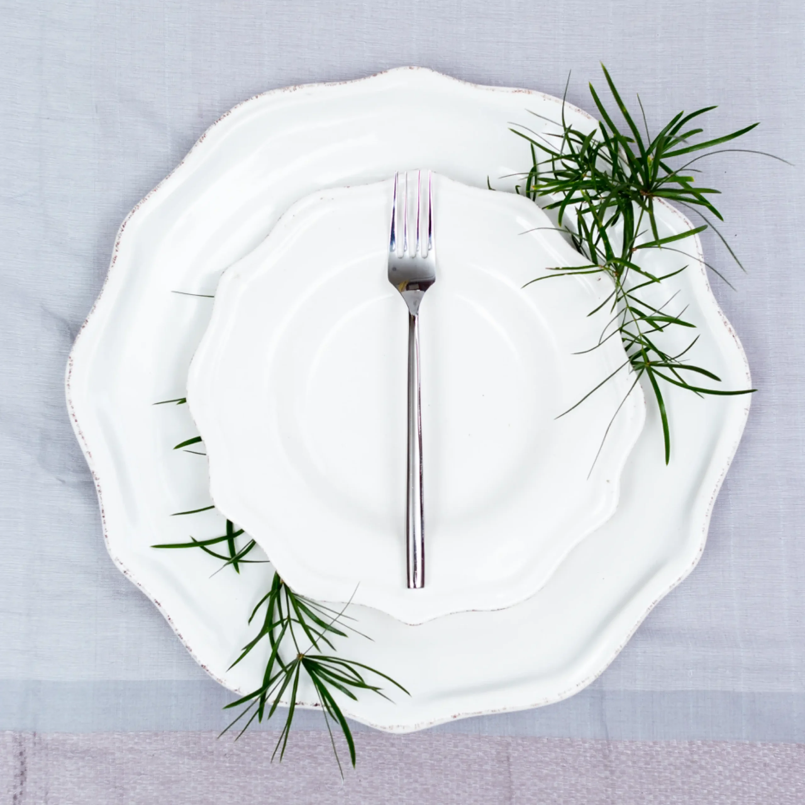 Handcrafted stainless steel dinner fork with cylindrical handle on white ceramic plate, made in Pilimathalawa Kandy Sri Lanka