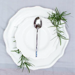 Handcrafted stainless steel teaspoon with hammered handle on white ceramic plate, made in Pilimathalawa Kandy Sri Lanka