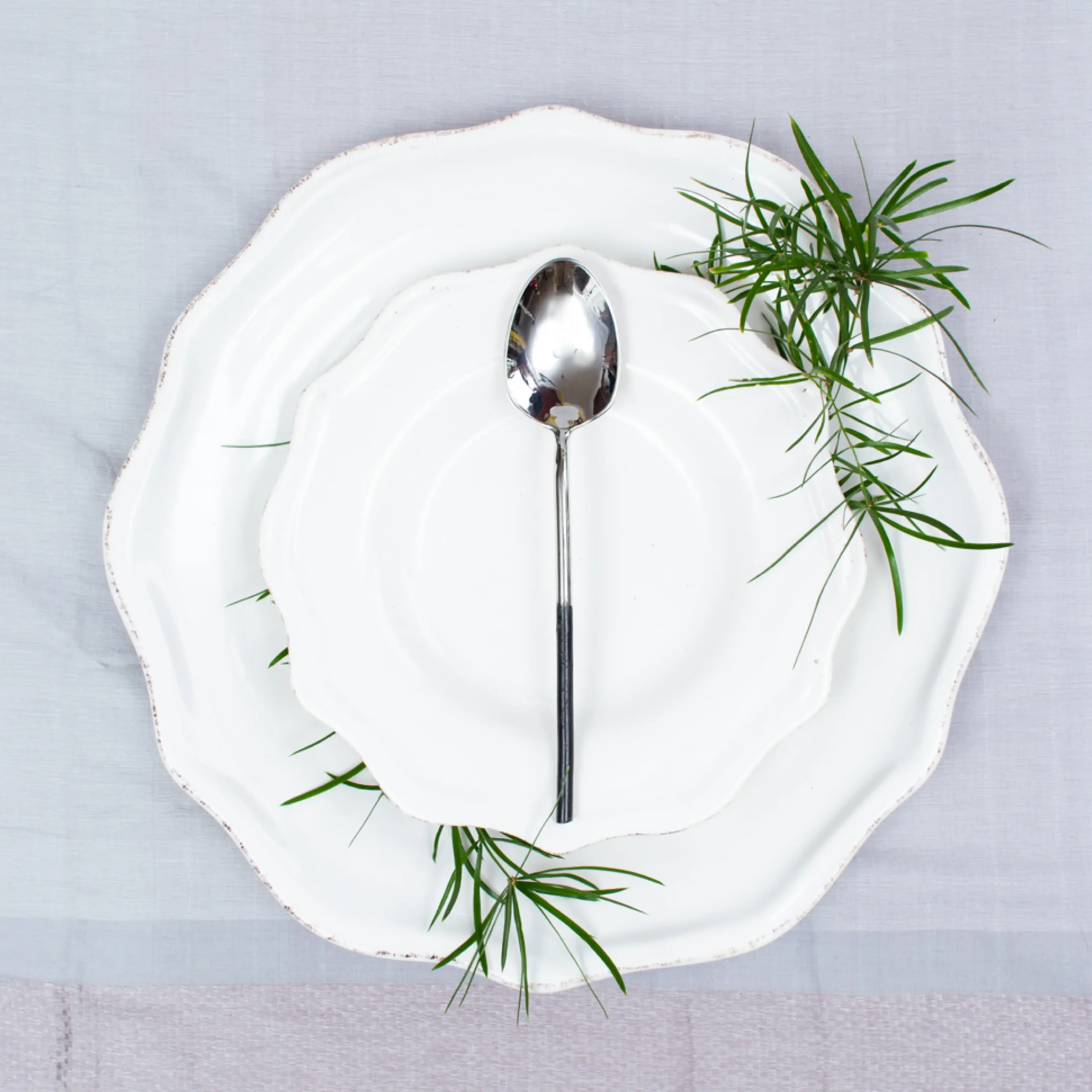 Handcrafted stainless steel tablespoon with black handle on white ceramic plate, made in Pilimathalawa Kandy Sri Lanka