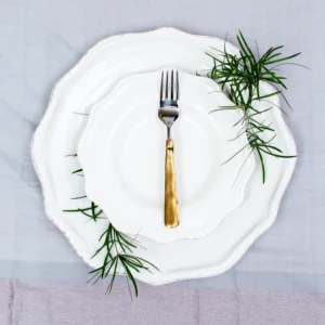 Handcrafted stainless steel table fork with brass handle on white ceramic plate, made in Pilimathalawa Kandy Sri Lanka