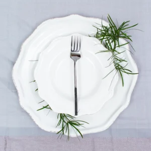 Handcrafted stainless steel spoon with black handle on white plate, made in Kandy Sri Lanka