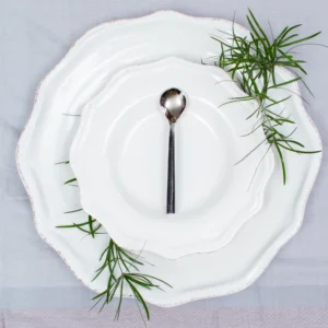Handcrafted stainless steel dessert spoon with oxidised dark handle on white ceramic plate, made in Pilimathalawa Kandy Sri Lanka
