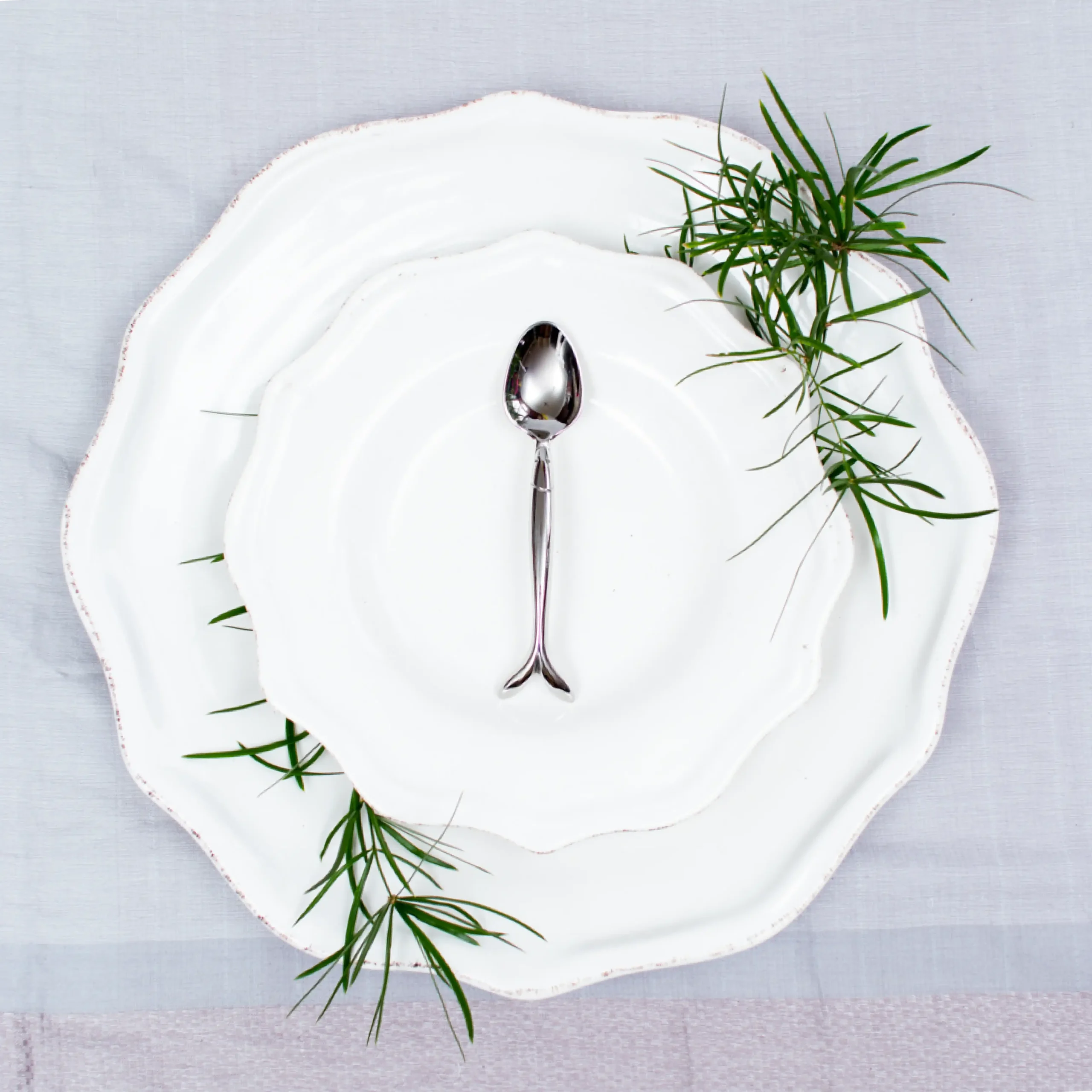 Handcrafted stainless steel teaspoon with fish handle on white ceramic plate, made in Pilimathalawa Kandy Sri Lanka